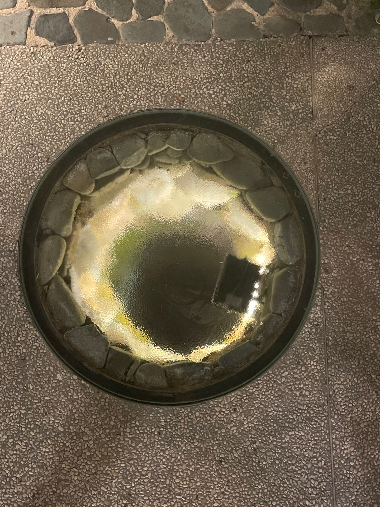 The traditional stone water basin set into the pebbled paving