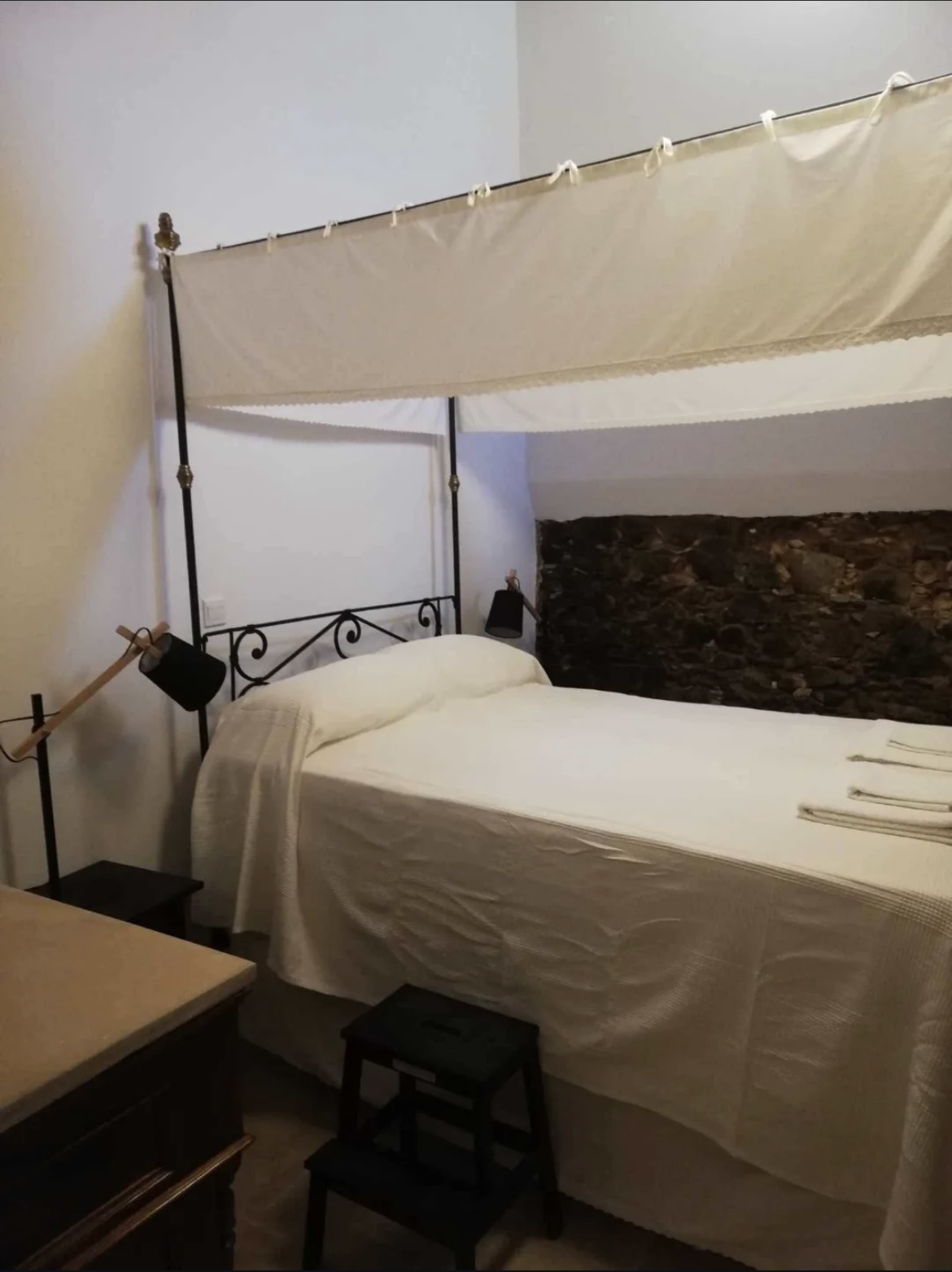 The elegant canopy bed against an exposed stone wall